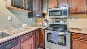 Una cocina con gabinetes de madera, un microondas de acero inoxidable y un horno.