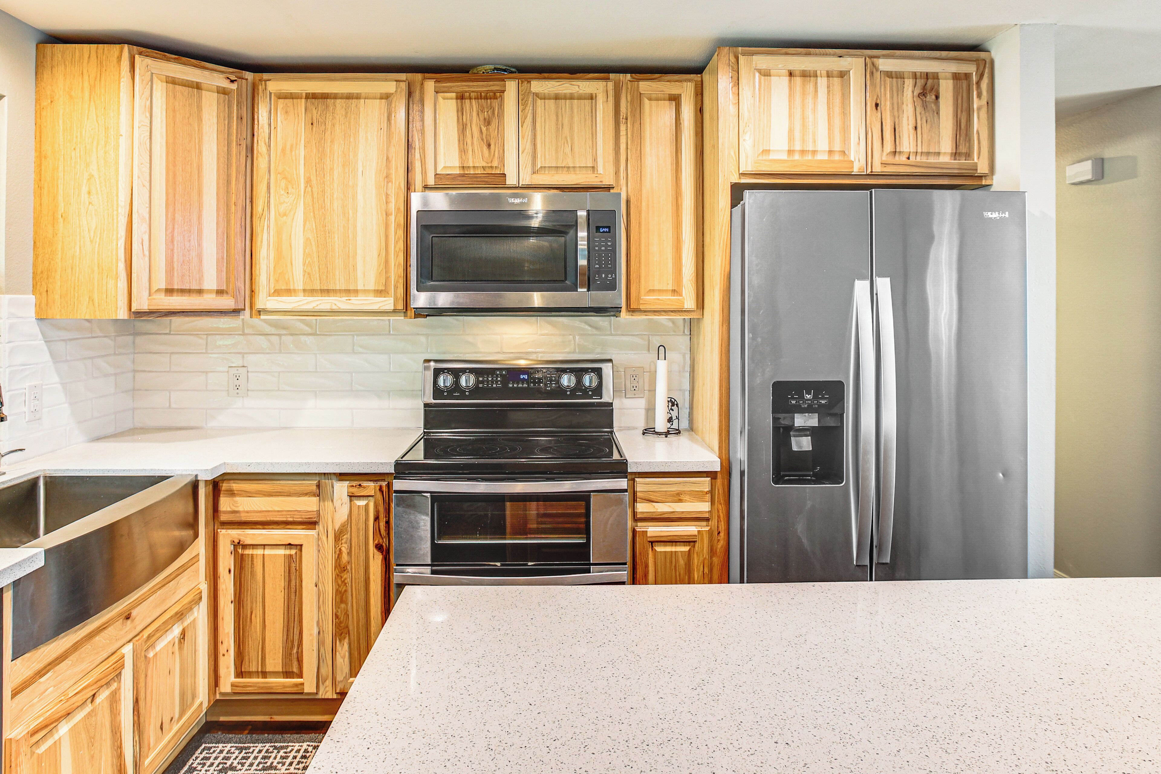 Una cocina con armarios de madera, un refrigerador de acero inoxidable, un microondas y una estufa.