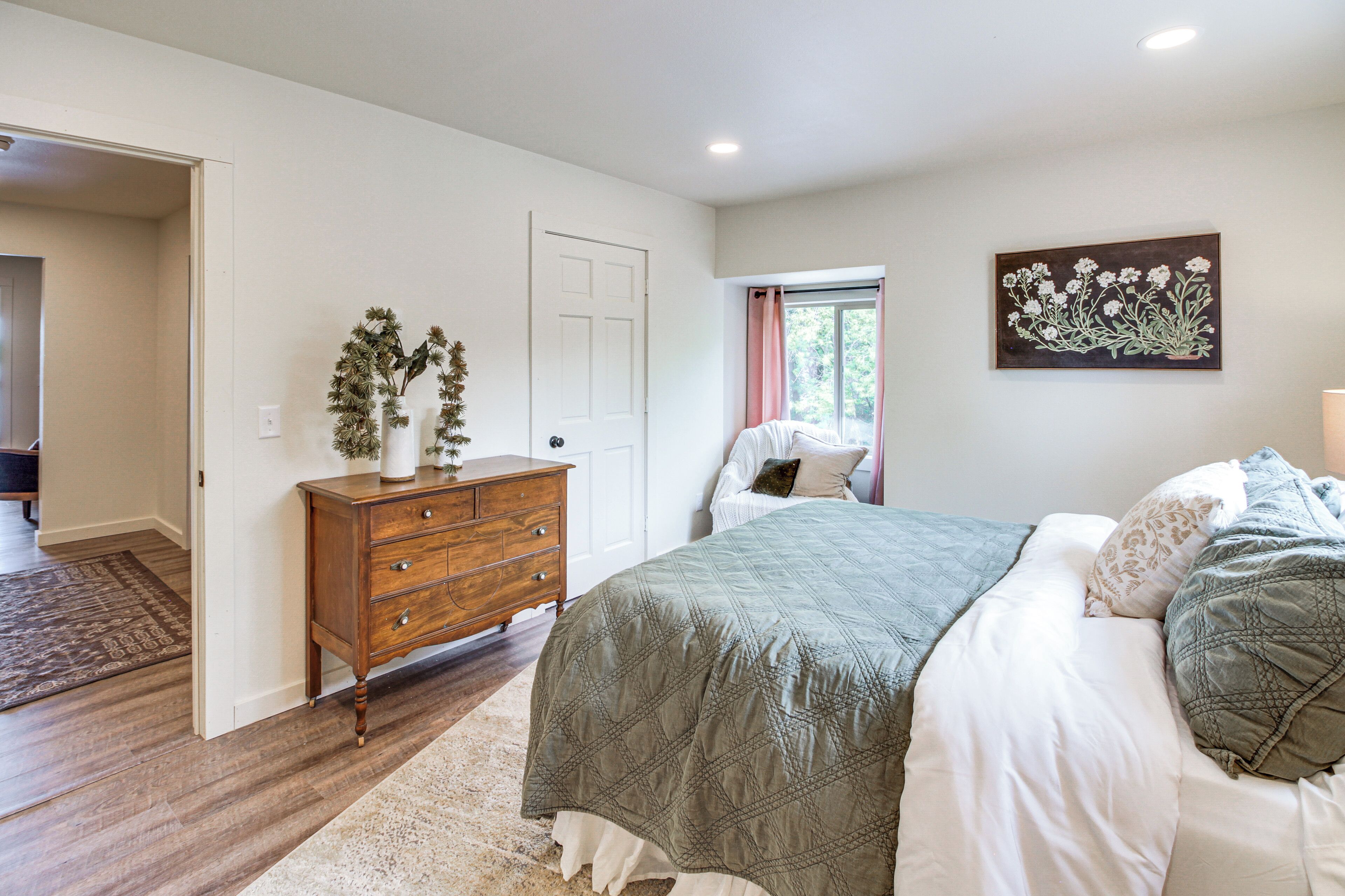 A bedroom with a bed, dresser, and a painting on the wall.