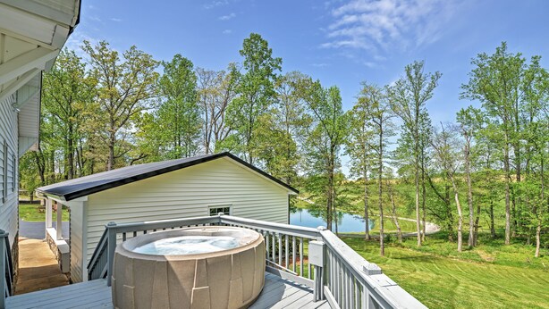 Une terrasse dotée d’un jacuzzi, d’un espace abrité et offrant une vue sur un lac entouré d’arbres.