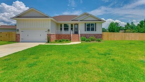 A single-story house with a garage, a front porch, and a well-maintained lawn. - Modern Family Home w/ Spacious Yard in Milton (Milton)