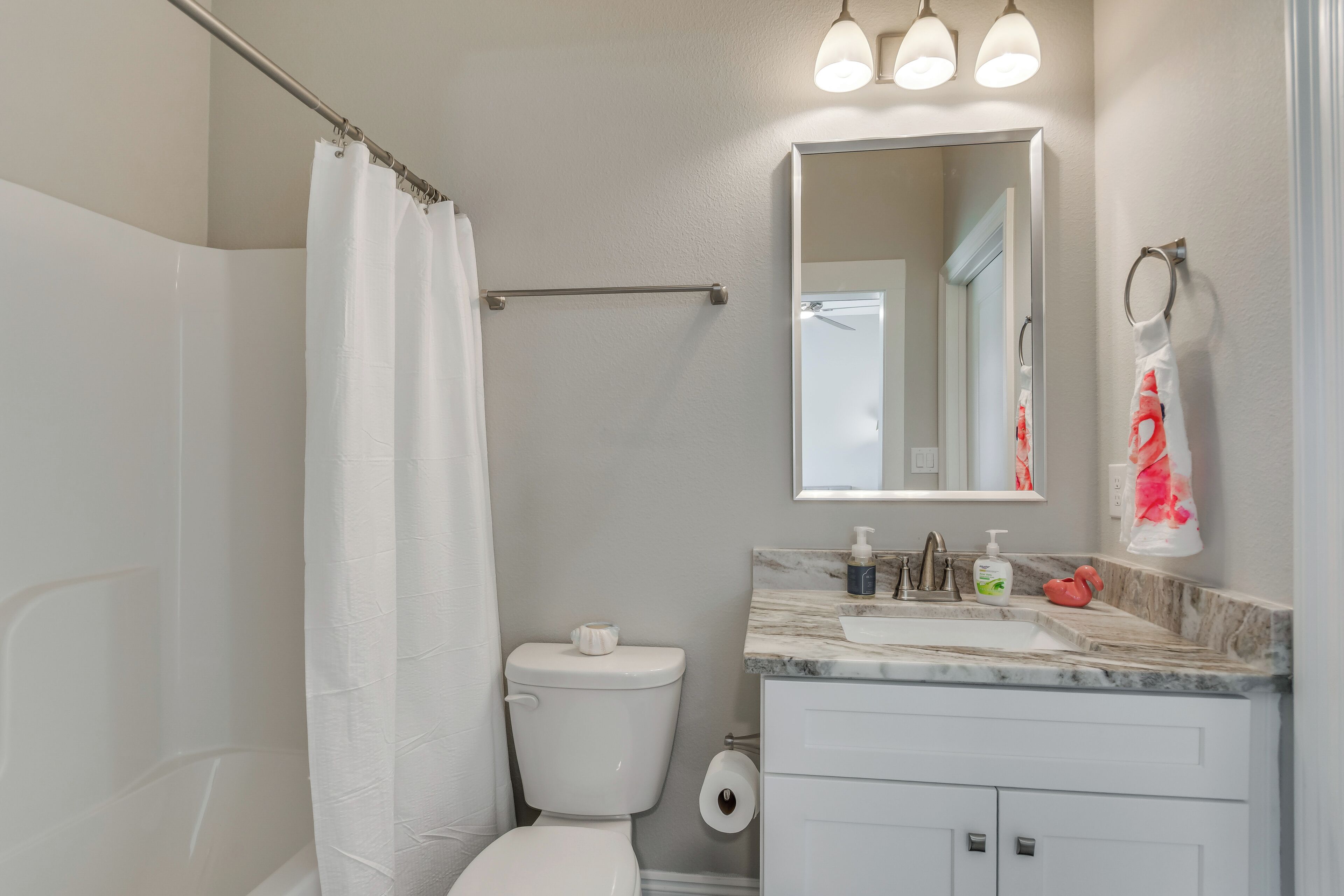 Ein Badezimmer mit Duschvorhang, Toilette, Waschbecken und Spiegel.
