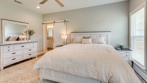 A bedroom with a large bed, a ceiling fan, a dresser, and a nightstand. - Modern Family Home w/ Spacious Yard in Milton (Milton)