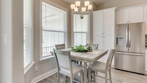 A kitchen with a dining table, chairs, a chandelier, and a refrigerator. - Modern Family Home w/ Spacious Yard in Milton (Milton)