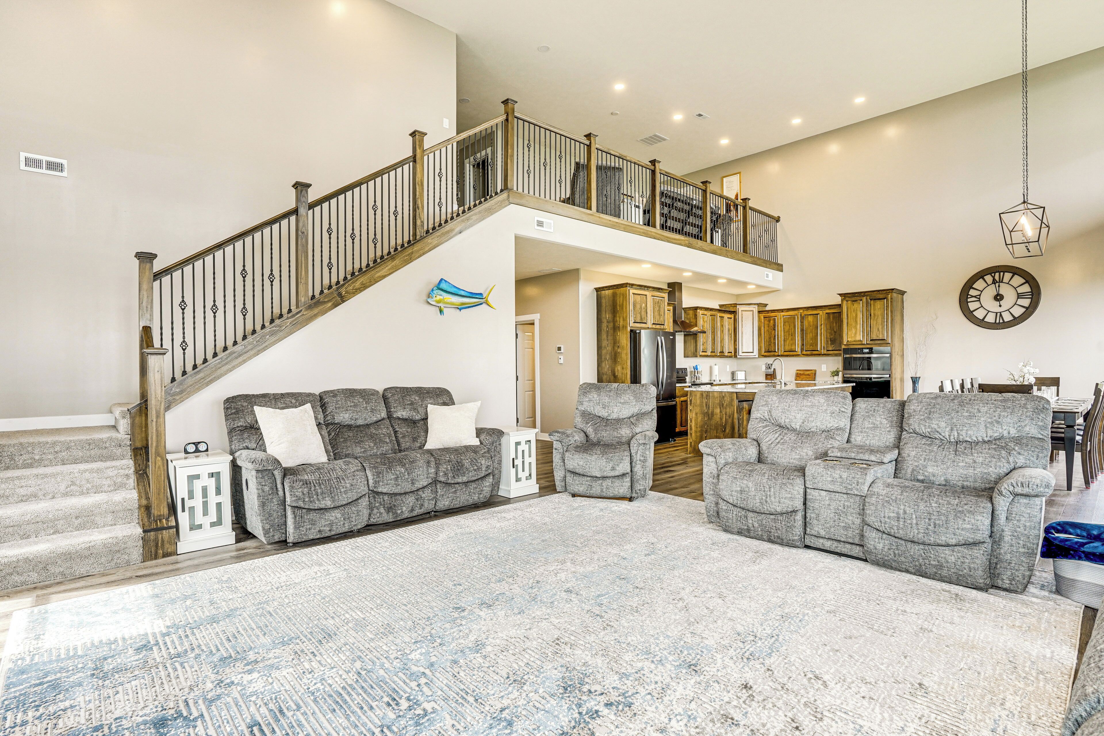 A spacious living room with a staircase leading to a second floor, a kitchen area, and a dining area.