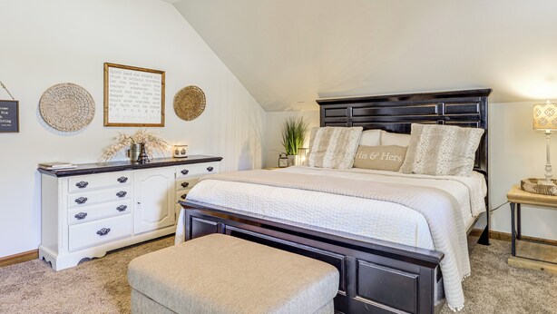 Ein Schlafzimmer mit einem großen Bett, einem Schminktisch, einer Bank und Wanddekoration.