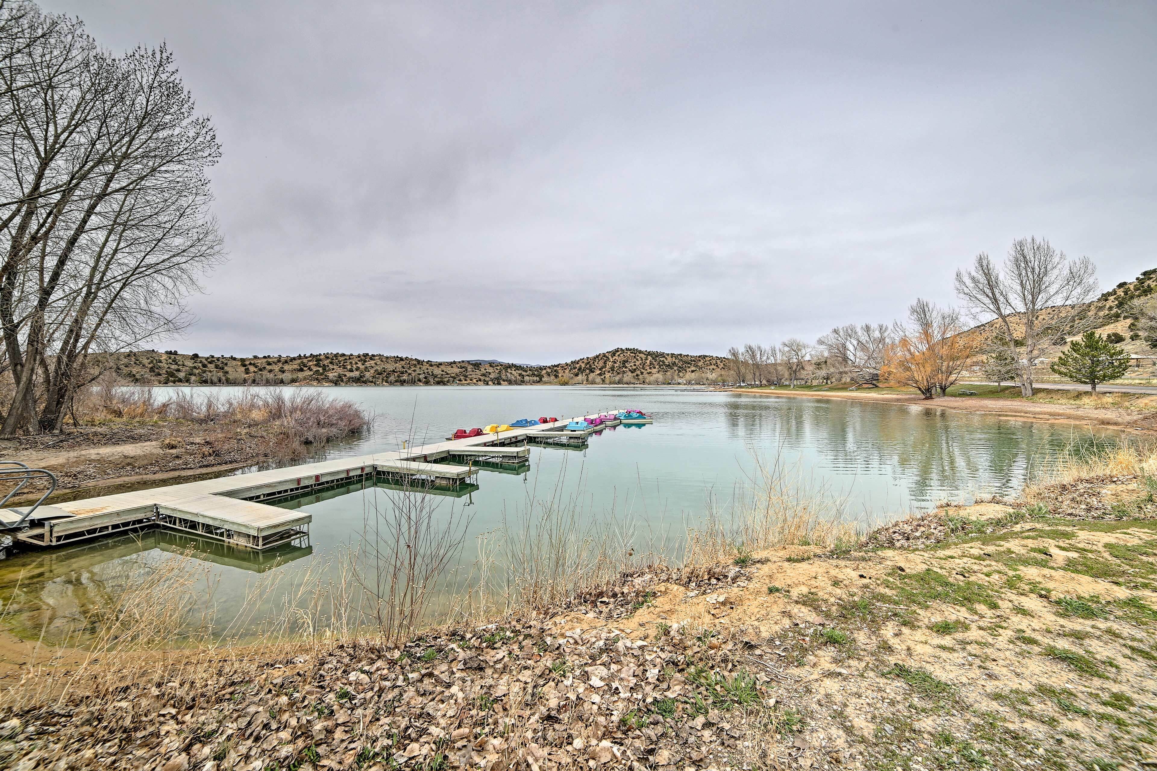 Un lac paisible avec un quai et des bateaux aux couleurs vives.