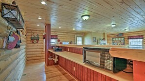 A log cabin interior with a kitchen area featuring a microwave, wooden cabinets, and a countertop. - Rustic Cabin Near Palisade State Park w/ Deck! (Sterling)