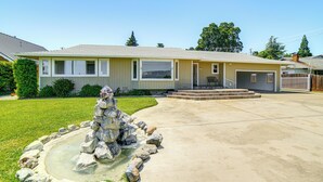 A two-story house with a front yard, a stone fountain, and a garage. - Steps to Clear Lake: Hot Tub Haven in Norcal! (Lakeport)