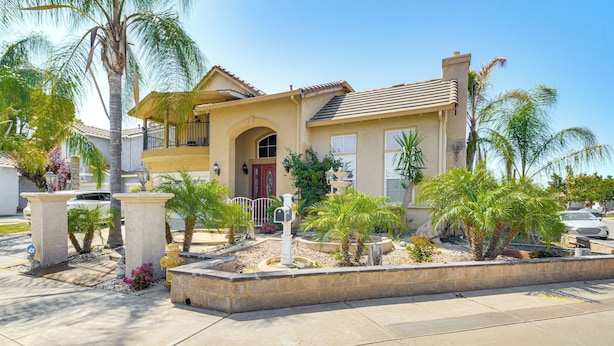 A two-story house with a balcony, surrounded by palm trees and a landscaped garden. - Golf, Fish & More: Cozy Safari Unit in Atwater! (Atwater)