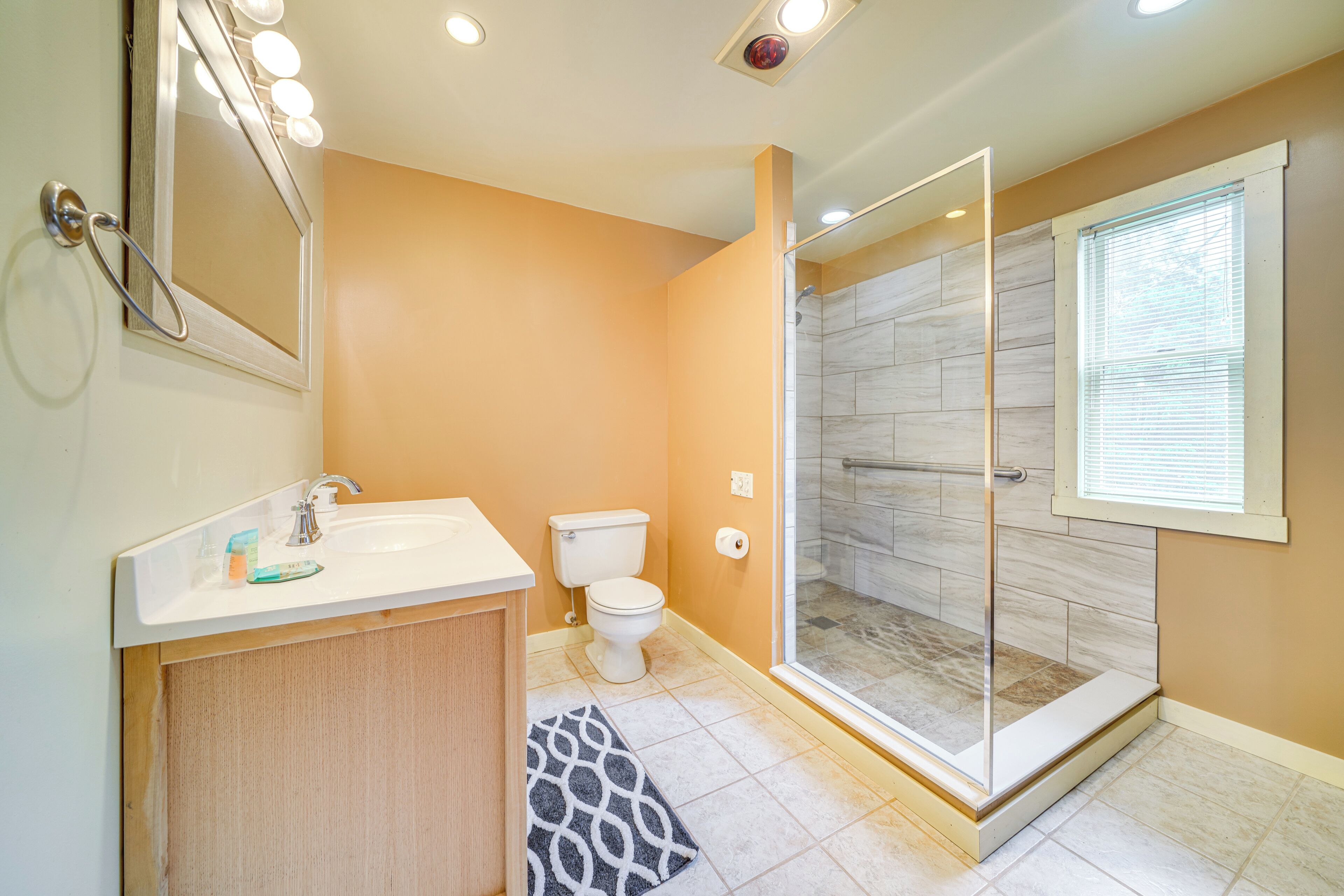 A bathroom with a shower, toilet, sink, and mirror.