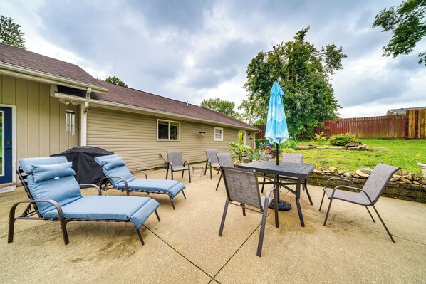 An outdoor patio with lounge chairs, a table, and an umbrella.