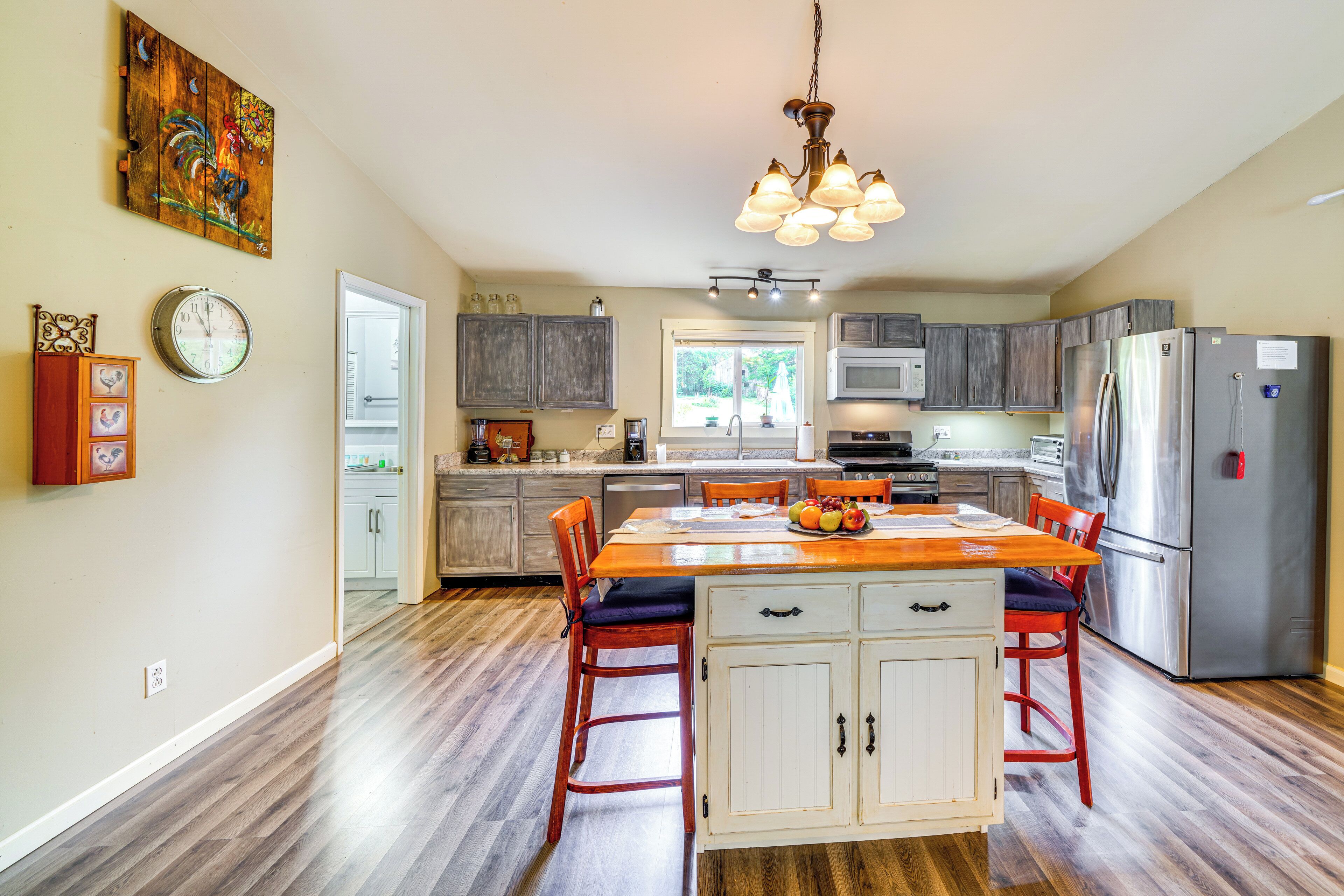 A spacious kitchen with wooden flooring, a central island, and modern appliances.