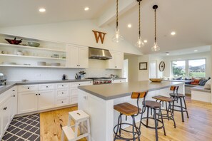 A modern kitchen with white cabinetry, a large island with bar stools, and pendant lighting. - Tranquil Santa Rosa Home w/ Private Pool & Views! (Santa Rosa)