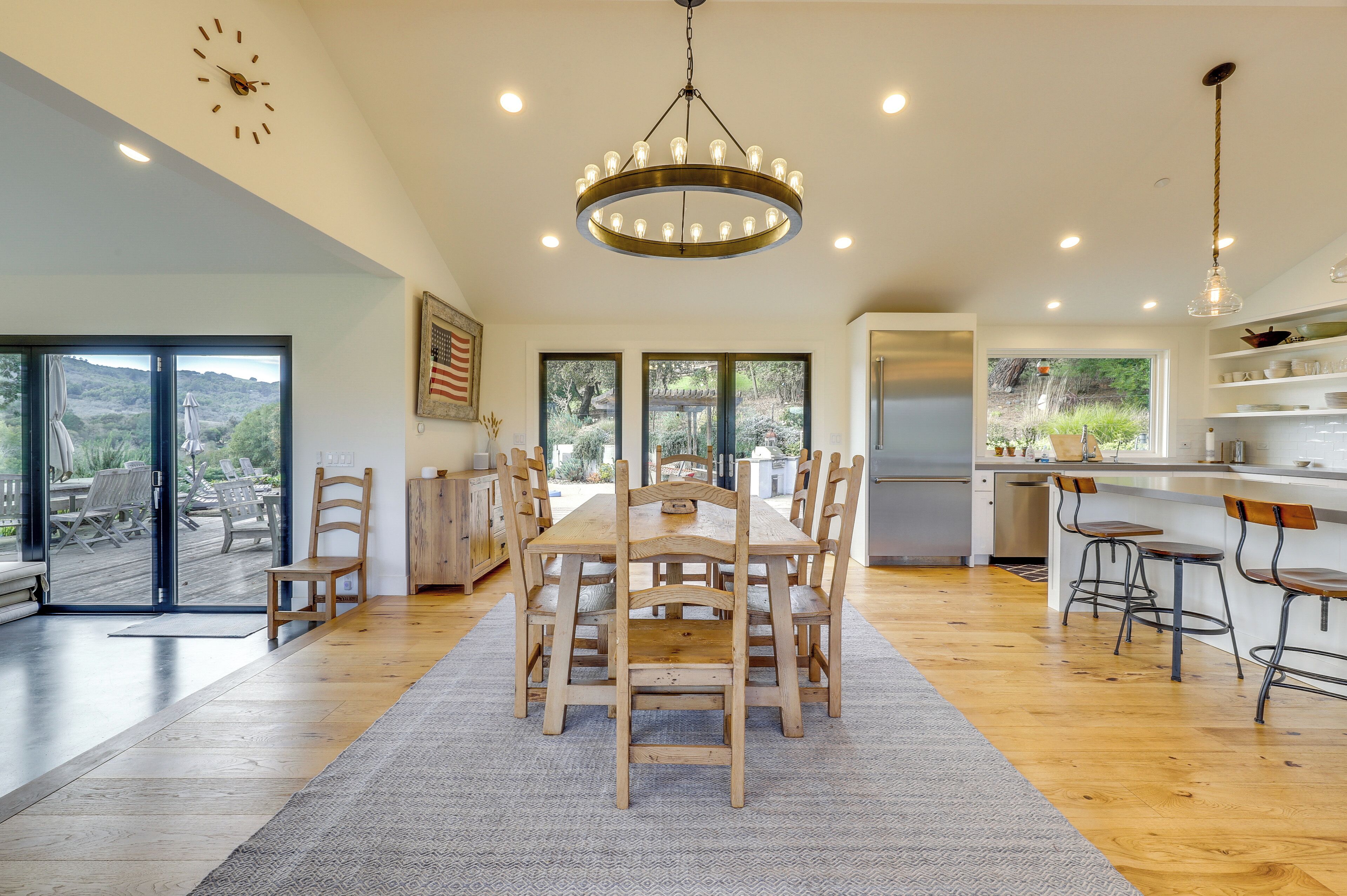 A spacious kitchen with a dining area, large windows, and a chandelier.