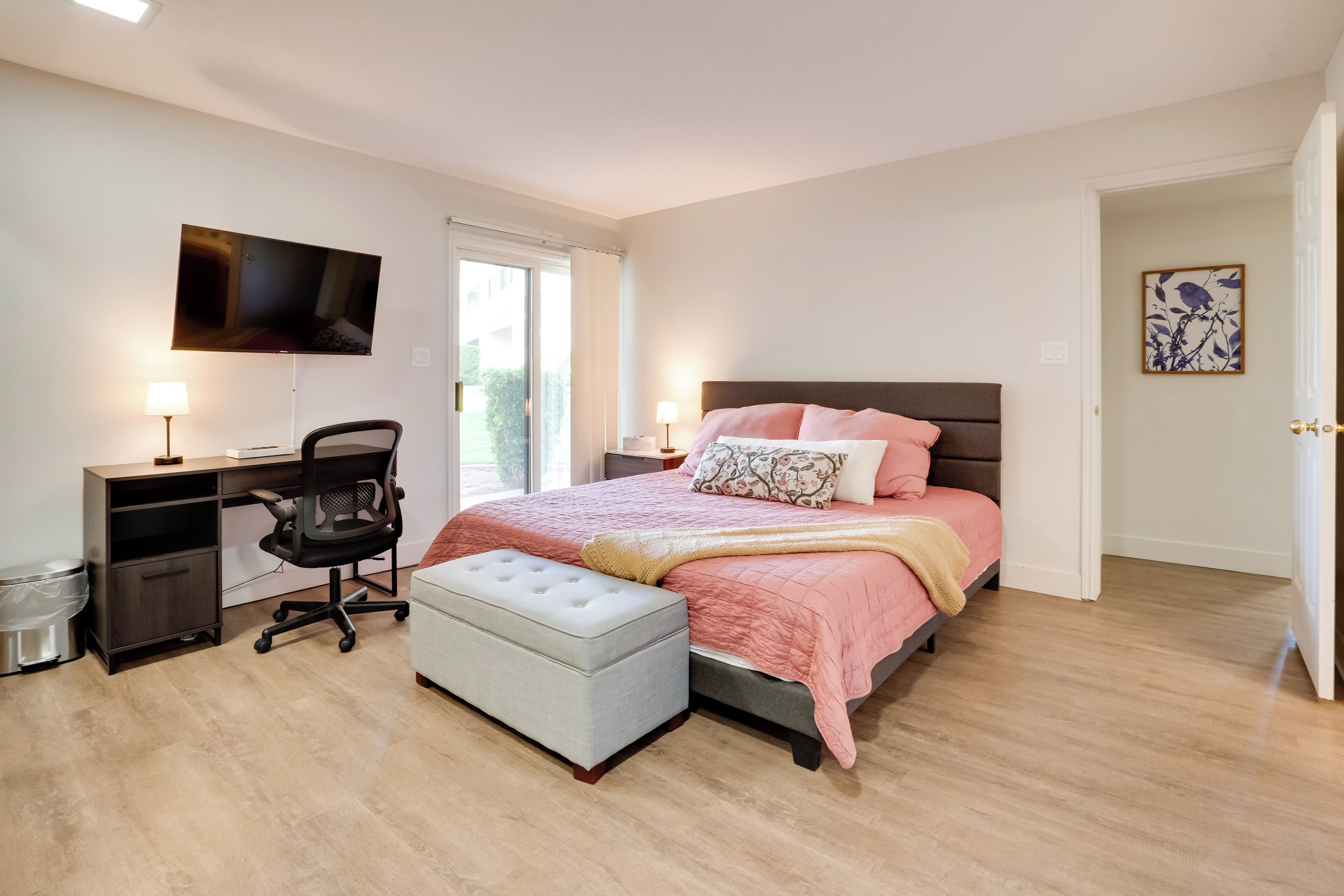 A bedroom with a bed, desk, chair, and a television on the wall.