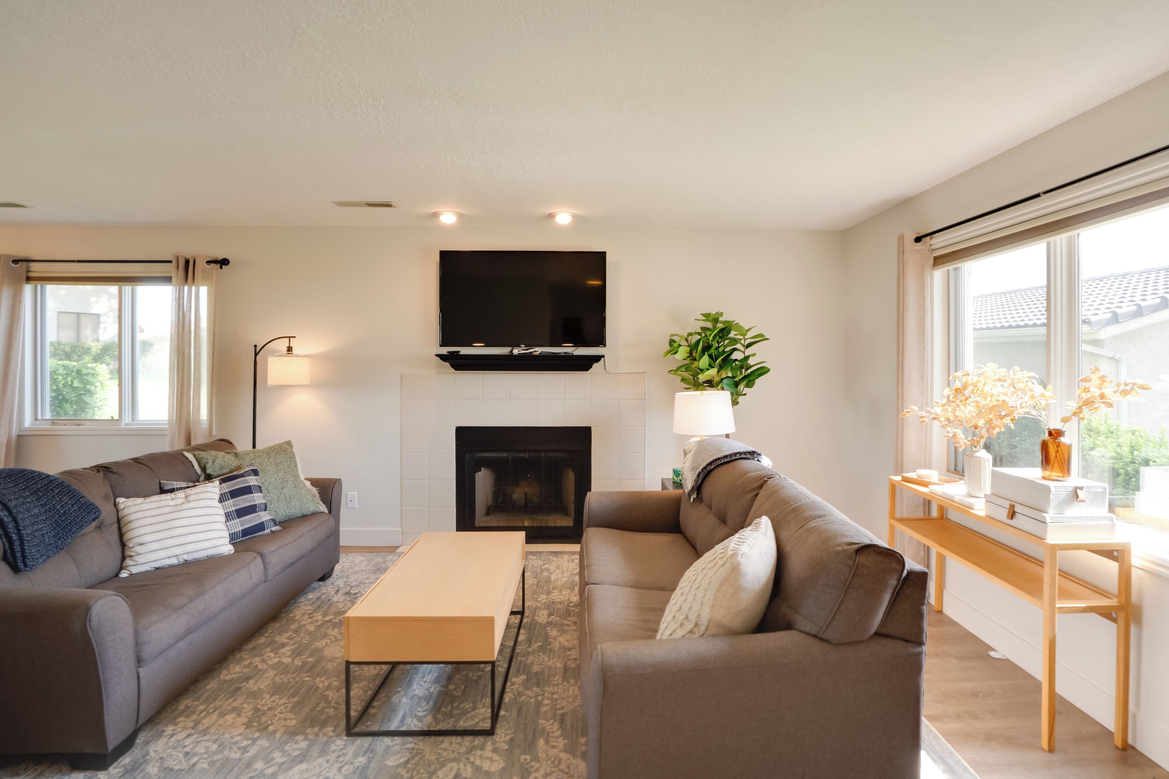 A modern living room with a fireplace, a flat-screen TV, a sofa, a coffee table, and a side table with decorative items.