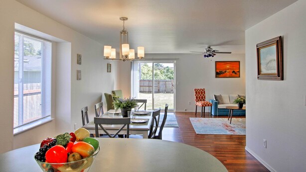 A dining area with a table set for four, a chandelier, and a view of the backyard through glass doors. - Central Tacoma Escape < 2 Mi From The Tacoma Dome! (Tacoma)
