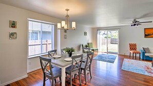 A dining area with a chandelier, a table set for four, and a view of the backyard through large windows. - Central Tacoma Escape < 2 Mi From The Tacoma Dome! (Tacoma)