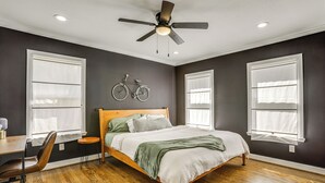 A bedroom with a wooden bed, a ceiling fan, and two bicycles mounted on the wall. - Condo 2 Mi to Houston Zoo & Museum District! (Houston)