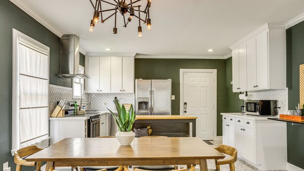 A kitchen with white cabinets, a wooden dining table, and a potted plant. - Condo 2 Mi to Houston Zoo & Museum District! (Houston)
