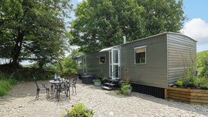 A mobile home with a patio area, outdoor seating, and potted plants. - Gwybedog (Llanwrda)