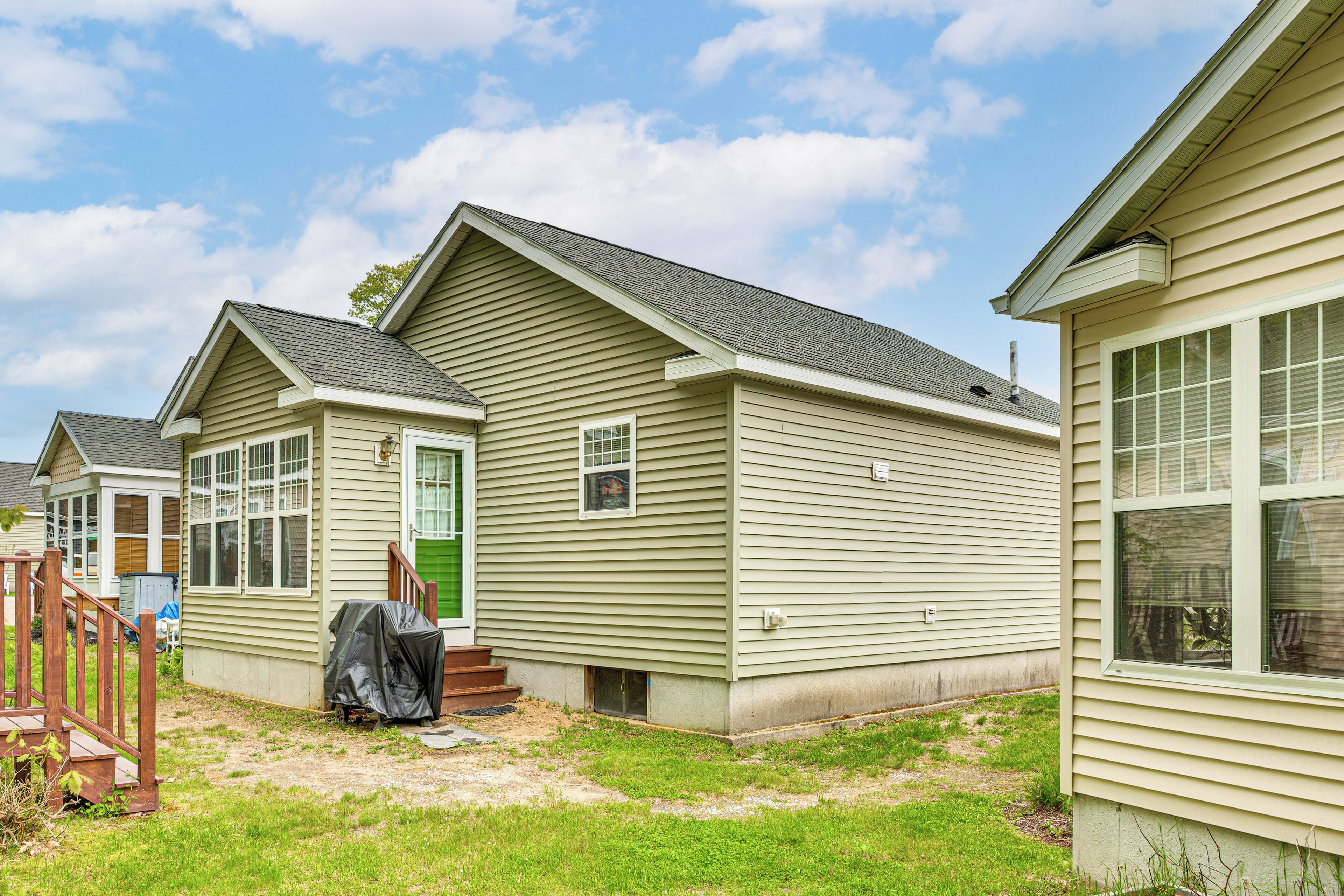 A single-story mobile home with a front porch, a small attached garage, and a covered outdoor area.