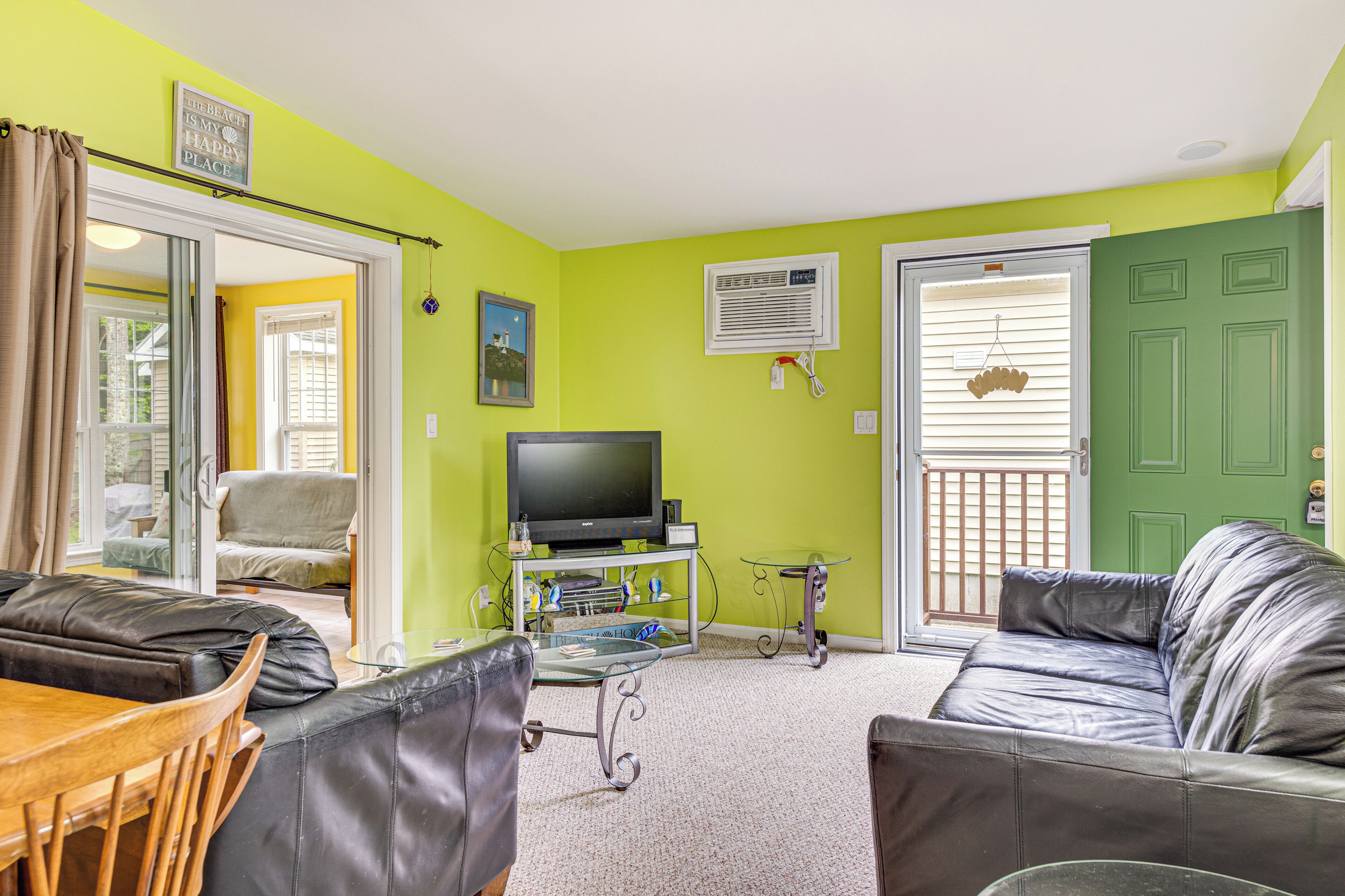 A living room with a TV, leather sofas, a glass coffee table, and a dining area with chairs.