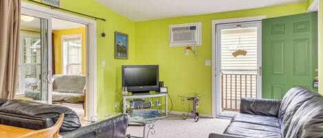 A living room with a TV, leather sofas, a glass coffee table, and a dining area with chairs.