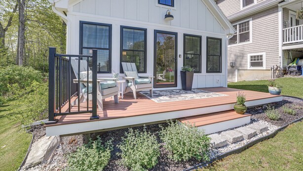 A white house with a wooden deck, large windows, and a small porch with outdoor furniture. - Oceanfront Studio w/ Private Dock in Harpswell! (Harpswell)