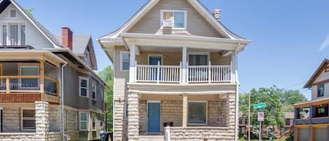 Une maison à deux étages avec une façade en pierre, une porte d’entrée bleue et un balcon à l’étage supérieur.