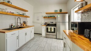 A kitchen with white cabinets, wooden countertops, a stainless steel refrigerator, an oven, and a microwave. - Modern 2BR Kansas City Condo Near Downtown (Kansas City)