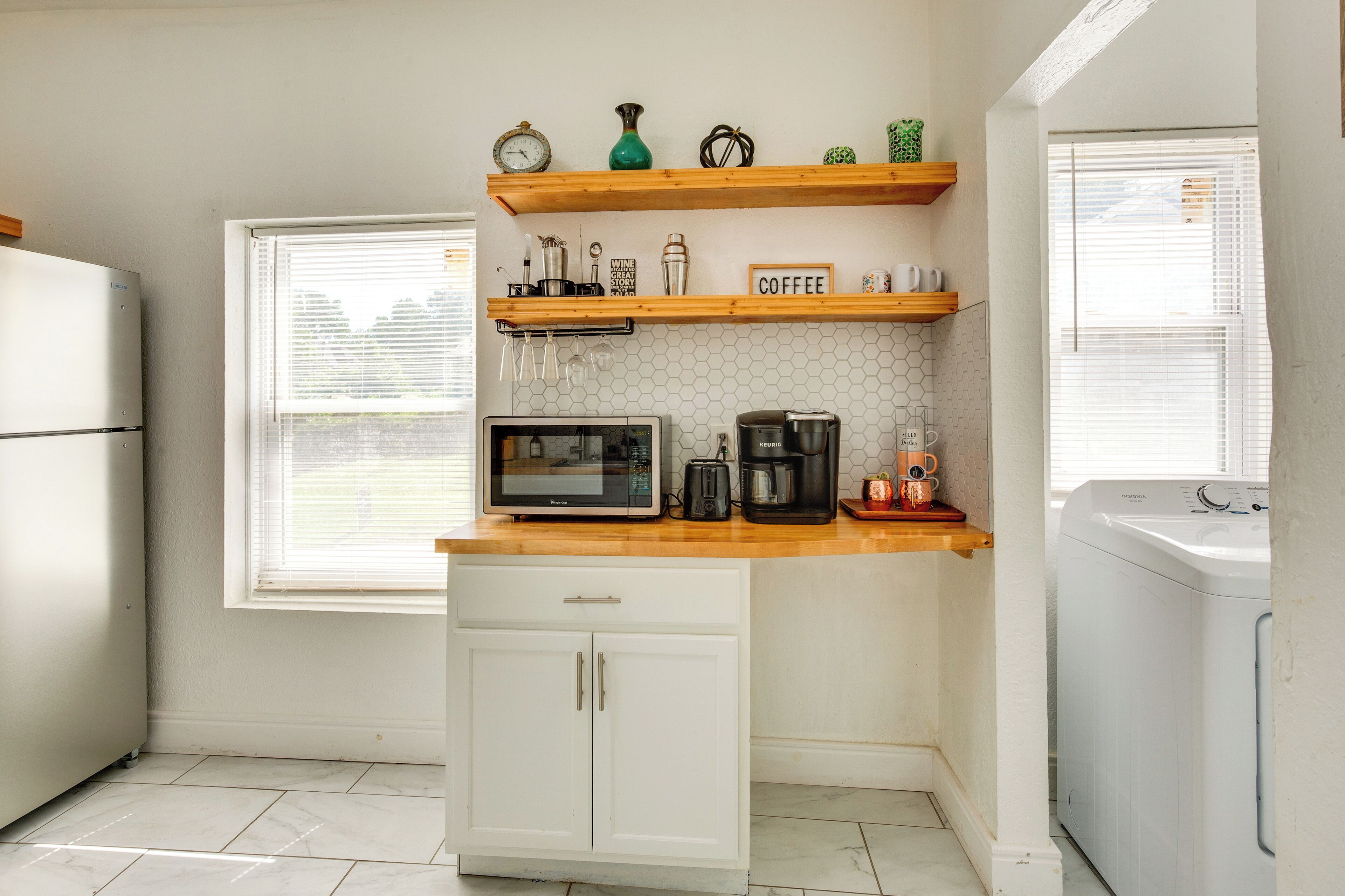 A compact kitchen with a microwave, coffee maker, and a coffee shelf.