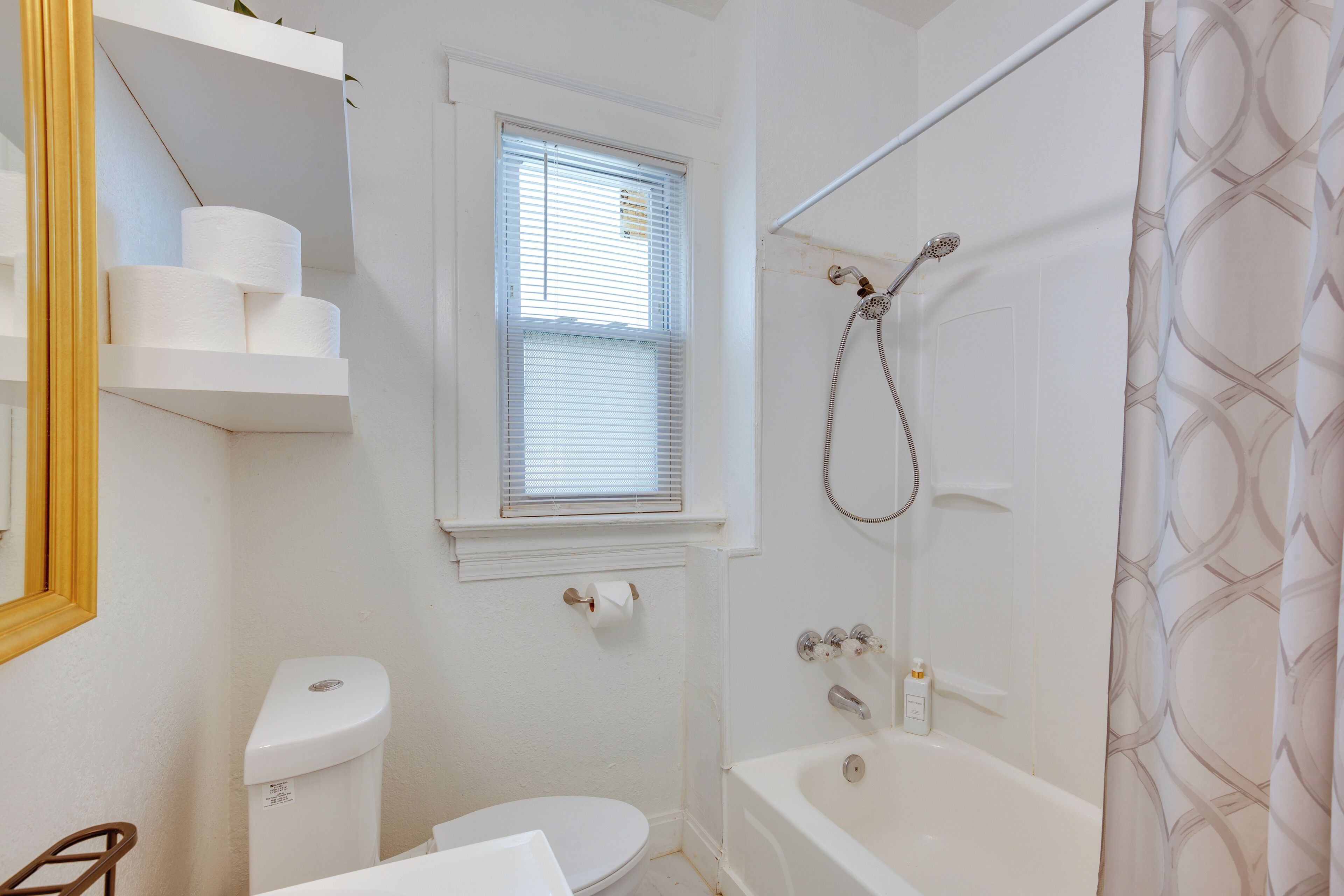 A small, white bathroom with a toilet, a window, a shower, and a bathtub.