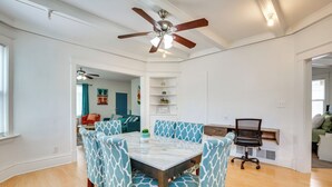 A dining area with a marble table and patterned chairs, a ceiling fan, and a view into a living room with a sofa and a TV. - Luxurious 2BR Kansas City Condo Near Downtown (Kansas City)