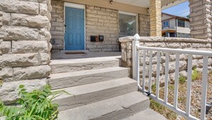 A stone building with a blue door, stone steps, and a white railing. - Luxurious 2BR Kansas City Condo Near Downtown (Kansas City)