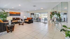 A spacious lobby with a sofa, armchairs, a coffee table, and a glass wall with tropical plants. - Outdoor Oasis: Marco Island Home Near Beaches (Marco Island)