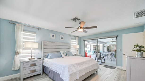 A bedroom with a bed, nightstands, a ceiling fan, and a view of the outside. - Outdoor Oasis: Marco Island Home Near Beaches (Marco Island)