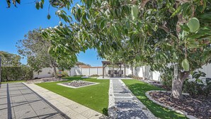 A well-maintained garden with a paved walkway, a pergola, and a lawn. - Outdoor Oasis: Marco Island Home Near Beaches (Marco Island)