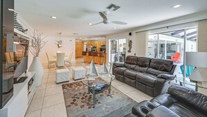 A modern living room with a leather sofa, a glass coffee table, and a white entertainment unit. - Outdoor Oasis: Marco Island Home Near Beaches (Marco Island)