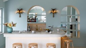 Een keuken met een centraal eiland, barstoelen en een hanglamp.