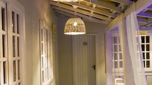 A hallway with a green floor, white walls, and a door labeled '10'. There are wicker lamps hanging from the ceiling. - Pousada Maresia Buzios (Buzios)