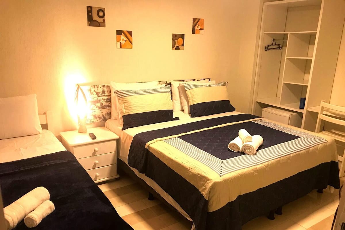 Habitación de hotel con dos camas, una mesita de noche, un armario y una pared decorada con arte abstracto.