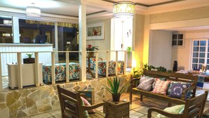 A cozy lounge area with a stone wall, wooden furniture, and a view of the outside. - Pousada Maresia Buzios (Buzios)