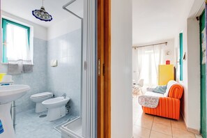 A bathroom with a shower, toilet, and sink. - Cute apartment with a balcony. (Minturno)