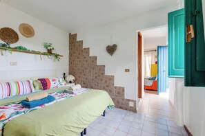 A bedroom with a bed, a staircase, and a door. - Cute apartment with a balcony. (Minturno)