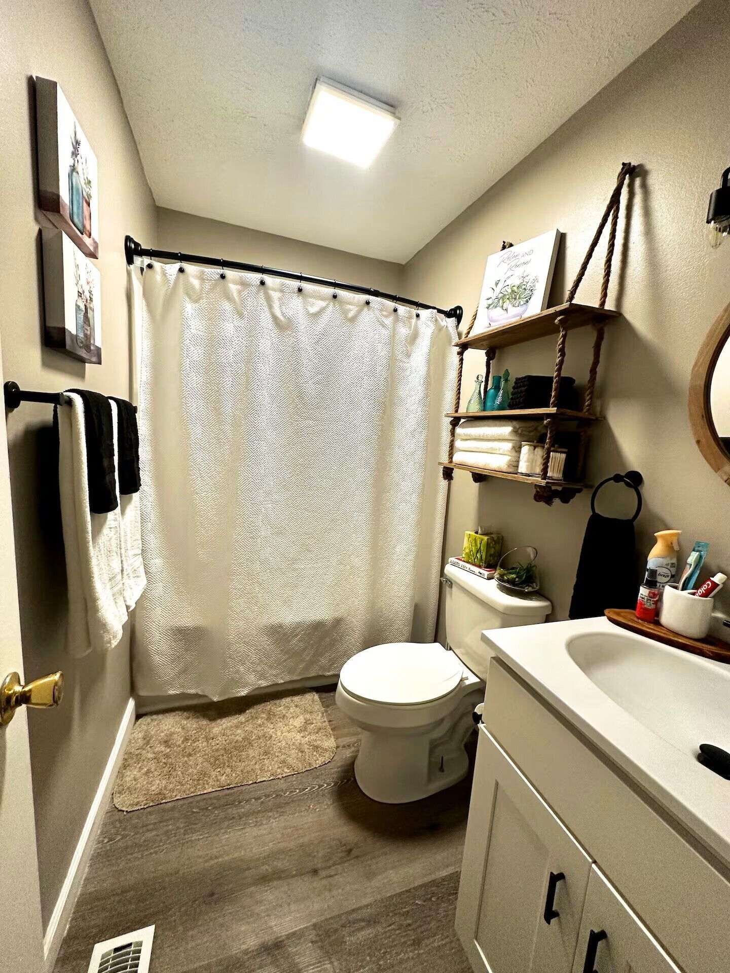 Une salle de bain équipée de toilettes, d’un lavabo, d’un rideau de douche et d’un porte-serviettes.