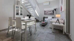 Una sala de estar moderna con comedor, una escalera y un ventanal grande.