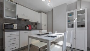 Una cocina moderna con armarios blancos, un microondas y una mesa de comedor con sillas.