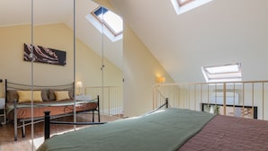 A bedroom with a loft bed, skylights, a painting, and a view of the outdoors. - Loft Cioccolato by Wonderful Italy (Turin)